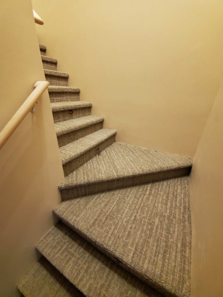 A beautifully carpeted winding staircase, showcasing expert installation by Integrated Flooring in Burton, MI.