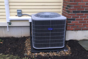 A newly installed Carrier outdoor AC unit next to a residential building by JM HVAC Pros in Elgin, IL.