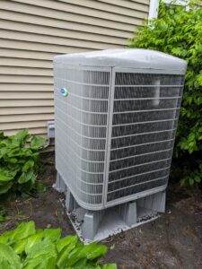 An outdoor Carrier air conditioner unit installed next to a residential home by Bloomington Heating & Air in Bloomington, MN.