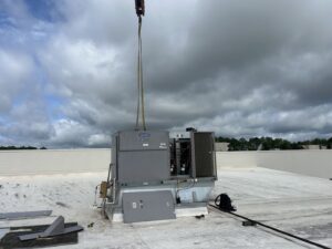 A Carrier commercial rooftop HVAC unit being lifted by a crane onto a building by Underwood Heating and Air Conditioning in Phenix City, AL