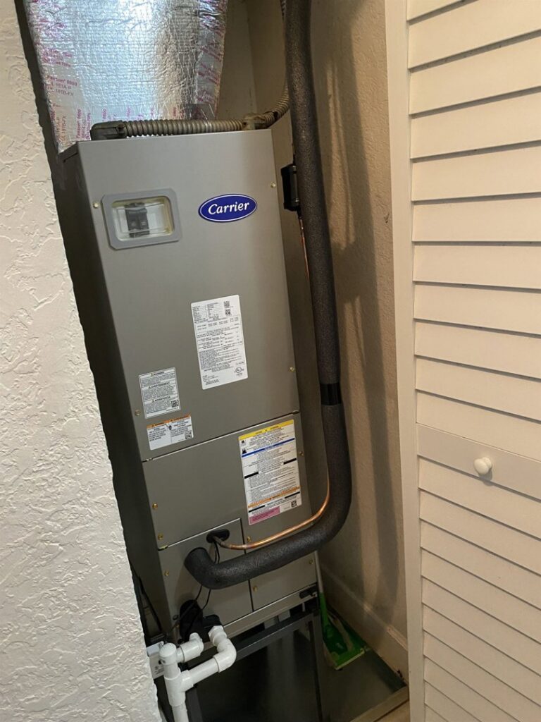 An indoor Carrier furnace or air handler unit installed in a utility closet by JM HVAC Pros in Elgin, IL.