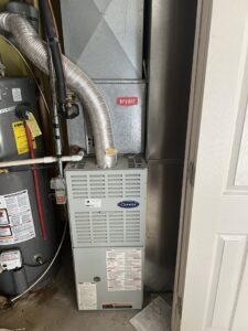 A Carrier furnace or air handler unit installed next to a water heater by TriForce HVAC in Layton, UT