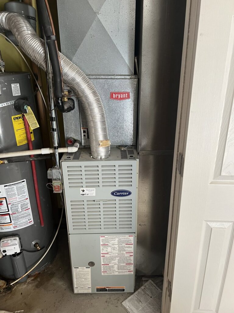 A Carrier furnace or air handler unit installed next to a water heater by TriForce HVAC in Layton, UT