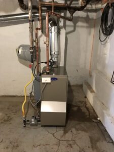 A Carrier brand furnace or boiler unit with piping installed in a utility room by Air Done Right in Philadelphia, PA.