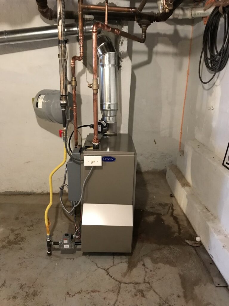 A Carrier brand furnace or boiler unit with piping installed in a utility room by Air Done Right in Philadelphia, PA.