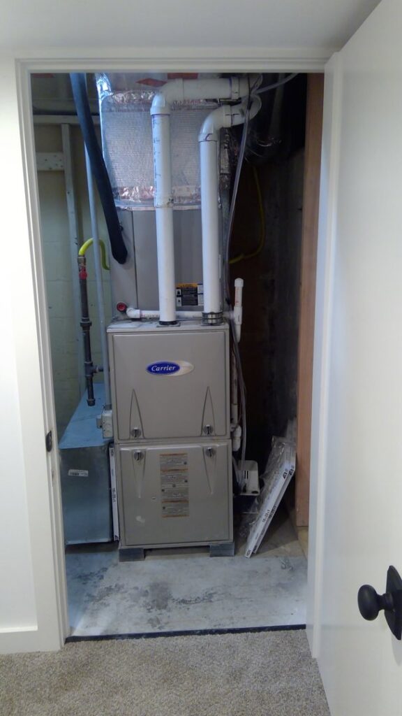 A Carrier brand furnace and air handler unit installed in a utility closet by Basic HVAC in Indianapolis, IN.