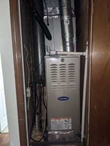 A Carrier furnace and air handler unit installed in a utility closet by Totality Heating And Cooling in Edmond, OK.