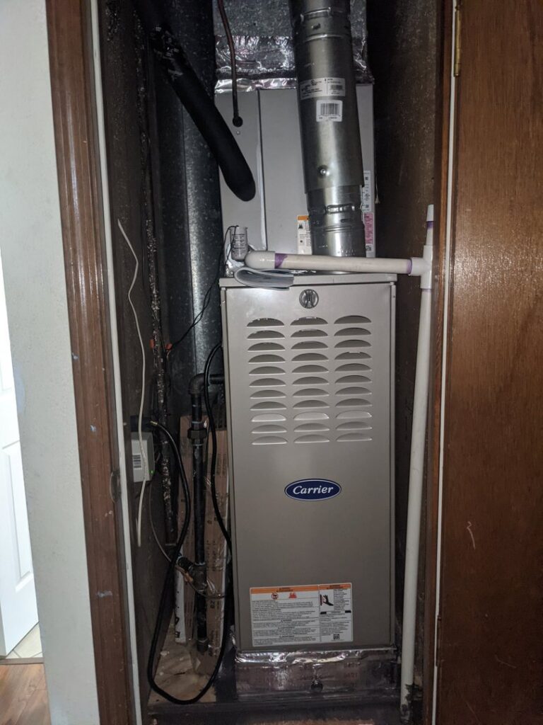 A Carrier furnace and air handler unit installed in a utility closet by Totality Heating And Cooling in Edmond, OK.