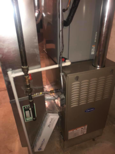 A Carrier brand furnace installation with associated ductwork and piping by Arrowhead Mechanical HVAC in Woodville, OH