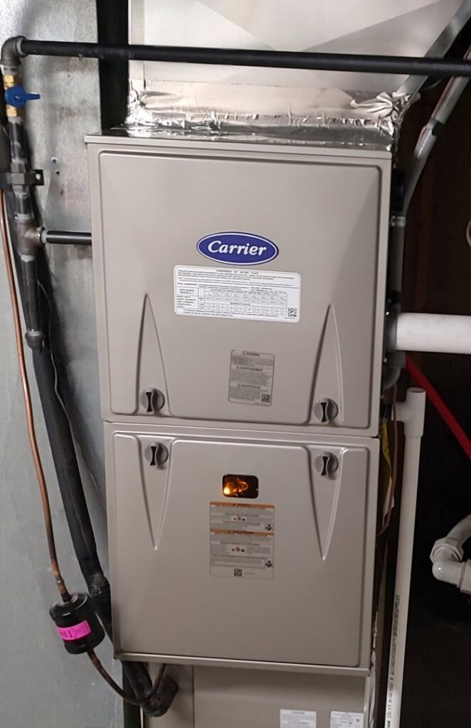 A Carrier furnace unit with a visible flame, indicating operation or testing by Wyles Heating & Air Conditioning Inc. in North Canton, OH.