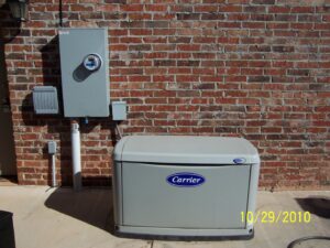 A Carrier generator and electrical meter installed on a brick wall by Generator Experts of Oklahoma in Norman, OK.