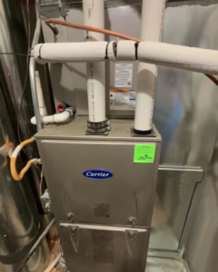 A newly installed Carrier HVAC furnace unit with insulated piping, showcasing professional installation by Trade Standard HVAC in Magna, UT.