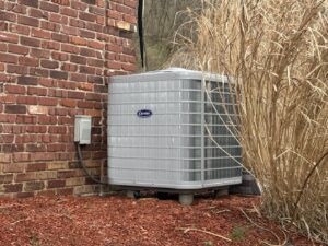 An outdoor Carrier HVAC unit installed next to a brick building, serviced by Delgado Enterprises in Pittsburgh, PA