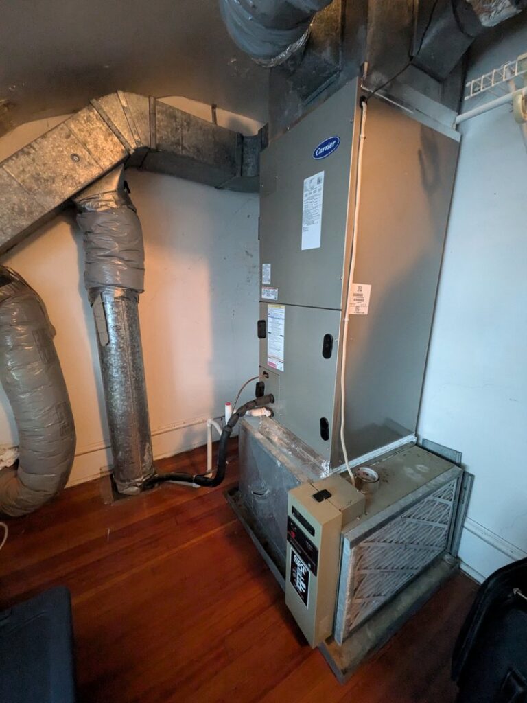 An indoor Carrier air handler unit with attached ductwork and a filter, installed by American Team Inc in Warminster, PA