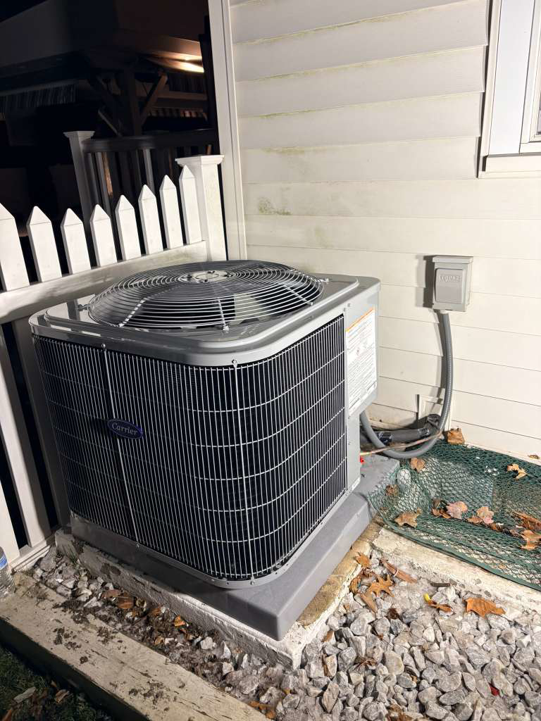 A Carrier outdoor air conditioning condenser unit installed beside a home by Fast Air in Zebulon, NC.