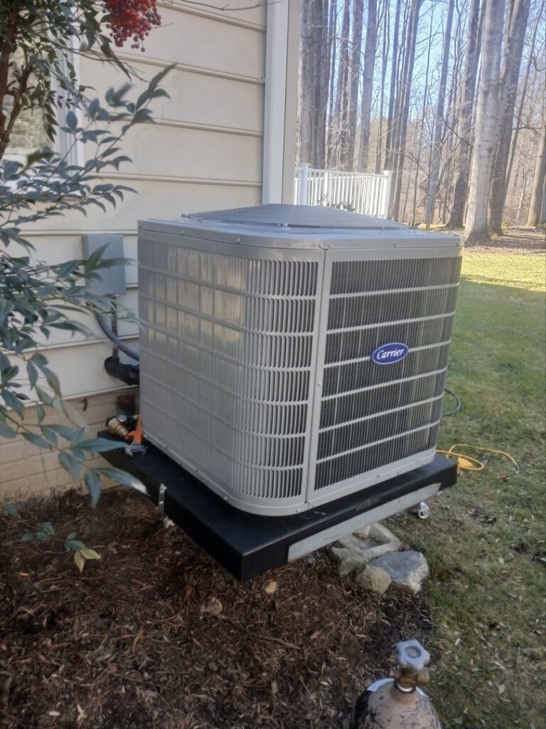 An outdoor Carrier AC unit installed next to a residential building by JDL HVAC Services, LLC in Laurel, MD.