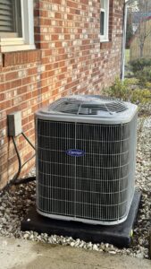 A newly installed Carrier outdoor air conditioning unit next to a residential home by Wyles Heating & Air Conditioning Inc. in North Canton, OH.