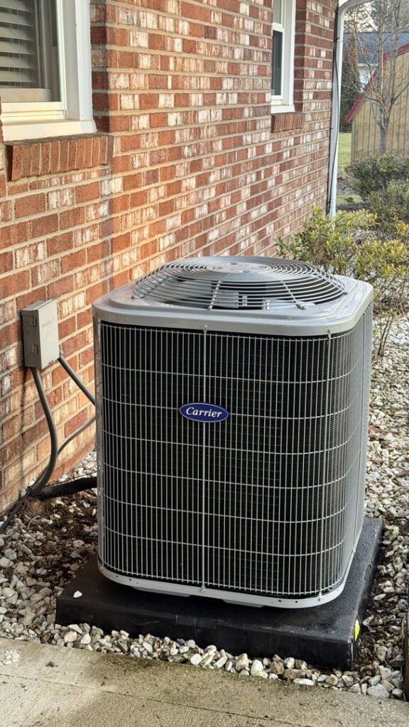 A newly installed Carrier outdoor air conditioning unit next to a residential home by Wyles Heating & Air Conditioning Inc. in North Canton, OH.