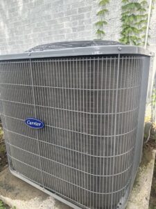 An outdoor Carrier air conditioning unit installed next to a brick wall by Summit Service Group in North Little Rock, AR.