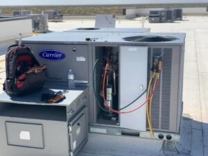 A Carrier rooftop HVAC unit with panels open and tools, ready for service or installation by EA Heating & Cooling in El Paso, TX.