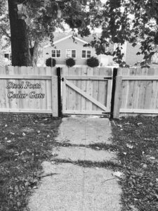 A cedar wood fence featuring steel posts and a matching gate, showcasing quality work by Thrive Fencing in Ames, IA.