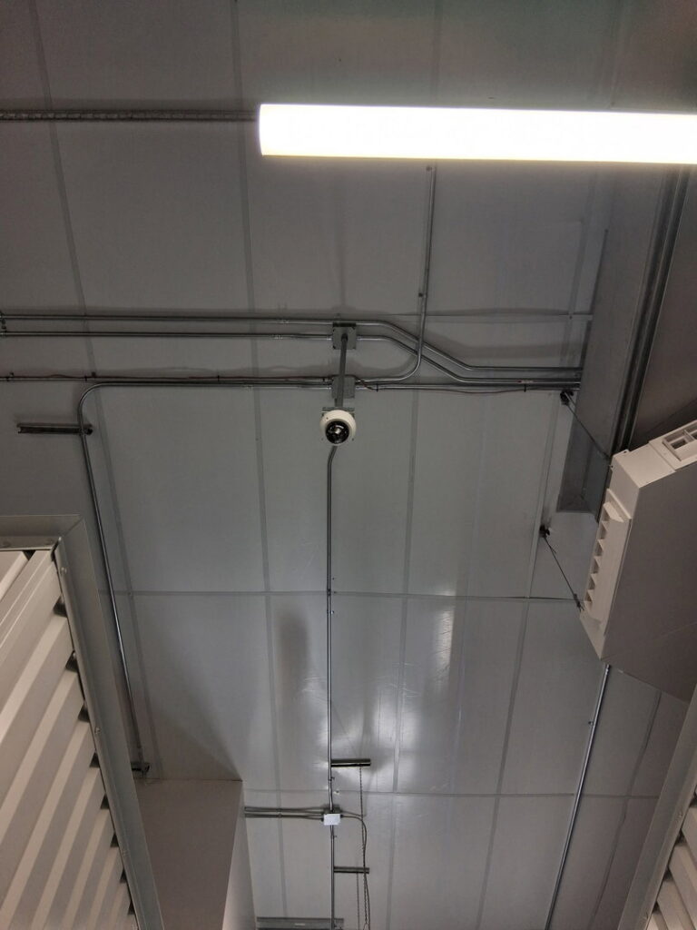 Overhead view of electrical conduits, wiring, and a security camera installation by Helm Electric in Salina, KS