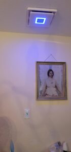 A ceiling exhaust fan with a blue light and a new light switch on the wall, installed by Ponce Electric in Houston, TX