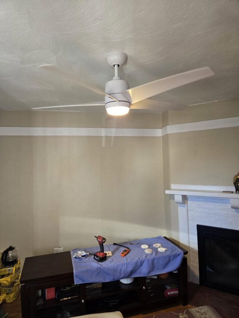 A newly installed ceiling fan with tools on a table below, indicating electrical work by DHJ Electric in Methuen, MA.