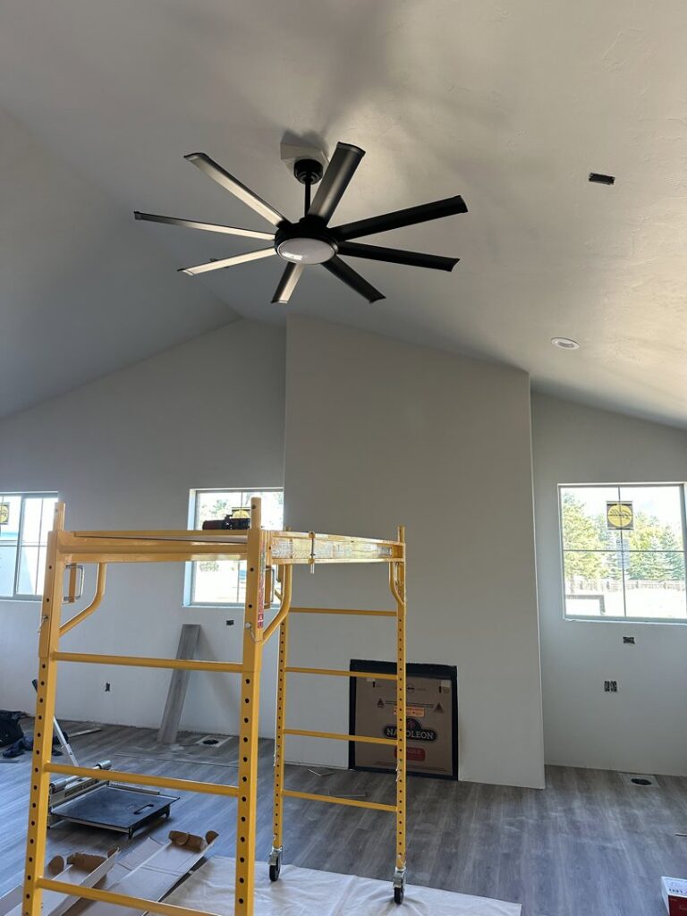 A large ceiling fan being installed in a room under construction, showing electrical work by Sunrise Electric LLC in Kalispell, MT.