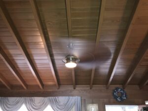 A ceiling fan with a light kit professionally installed on a wooden ceiling by Prime Electric in Bellevue, WA.