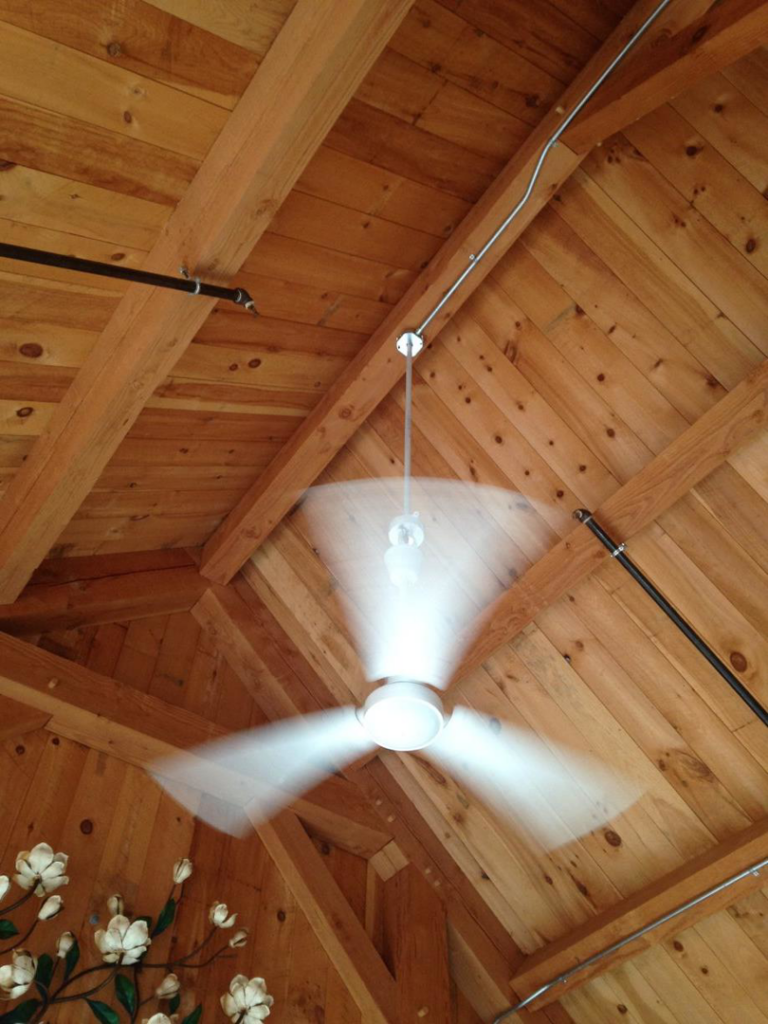 A spinning ceiling fan with lights installed on a wooden ceiling with exposed conduit by RightWay Electric RI in Providence, RI.