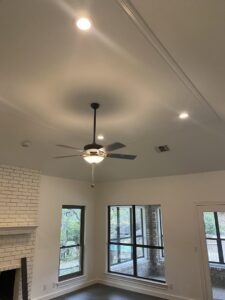 A newly installed ceiling fan and recessed lighting in a living room by Outlaw Home Services, LLC in San Antonio, Tx.