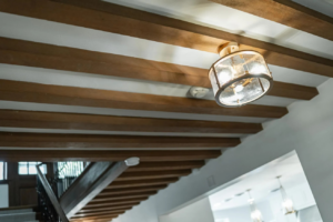 A ceiling with exposed beams showcasing a modern light fixture and smoke detector installed by Power Plus Electric LLC in Rochester, MN.