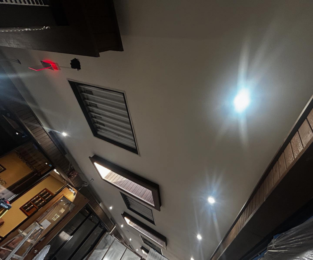 Ceiling lighting installation in progress with an open panel, exposed wiring, and a laser guide by Mechatronics LLC in Memphis, TN.