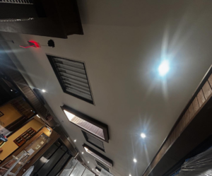 Ceiling lighting installation in progress with an open panel, exposed wiring, and a laser guide by Mechatronics LLC in Memphis, TN.