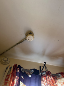 A ceiling-mounted smoke detector with electrical conduit installed by Dartmouth Fire Protection Electrical Division in New Bedford, MA.