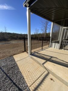 A black chain-link fence and a black aluminum gate installed on a patio area by TC Fencing LLC in Tuscaloosa, AL.