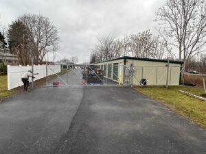 A worker installing a chain-link fence alongside a white vinyl fence by Camp Carlson Fencing in Rochester, NY.