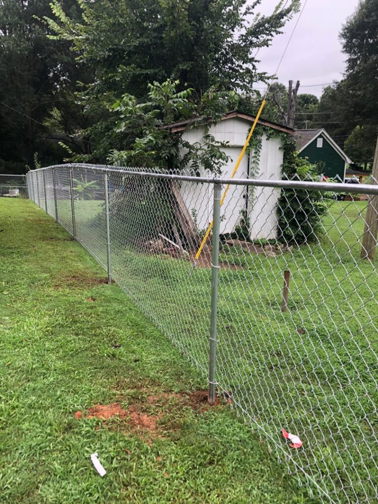 A newly installed chain-link fence enclosing a residential backyard by Fenceitforu LLC in Matthews, NC.