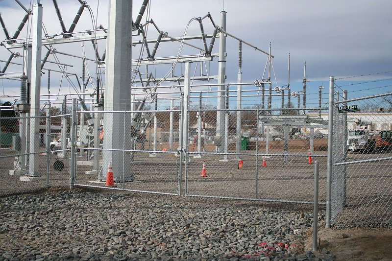 A chain-link fence with barbed wire protecting an electrical substation, installed by Life Time Fence, Inc. in Cedar Rapids, IA.