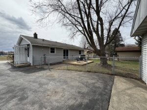 A chain link fence enclosing a residential backyard with a wooden deck, installed by Safe Yard Fence - Waukesha County in Waukesha, WI.