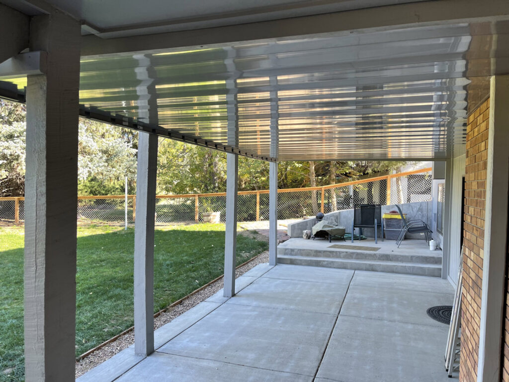 A backyard patio area with a chain-link fence visible in the background, installed by North CO Fence & Deck in Greeley, CO.
