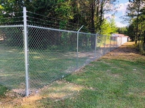 A chain-link fence with barbed wire for security, installed by LAV Fence LLC in Midlothian, VA.
