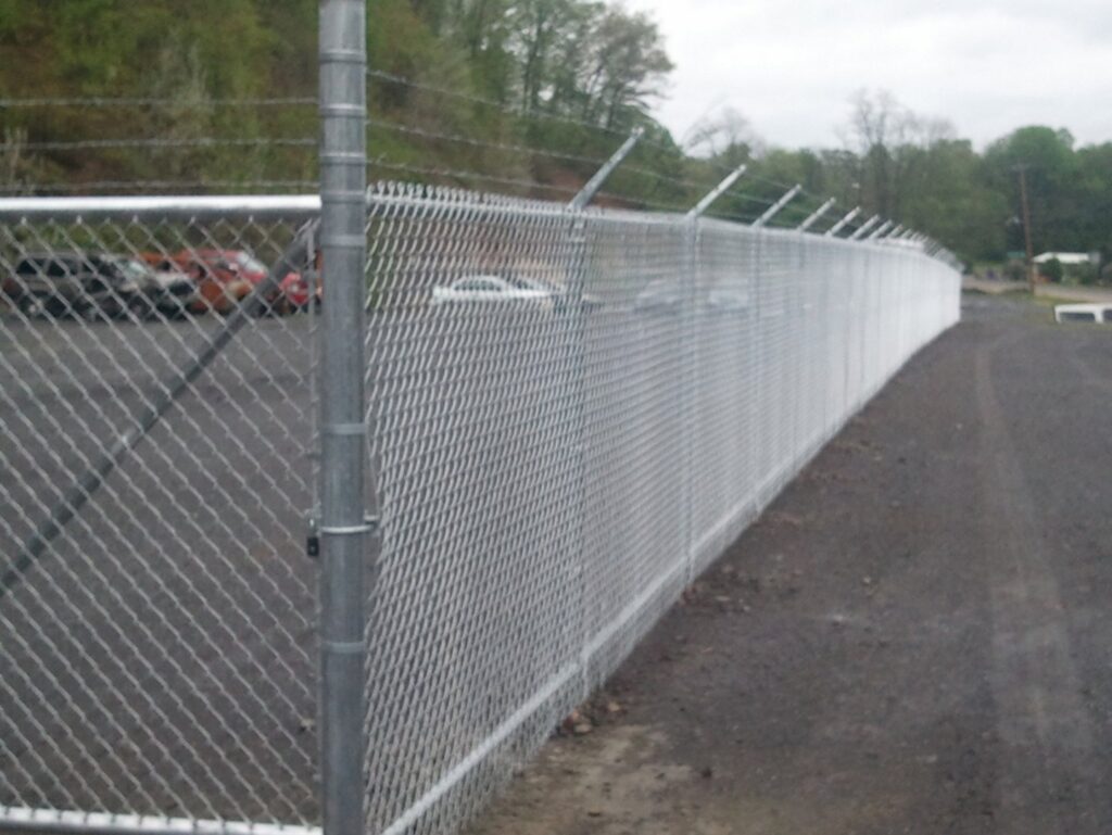 A long chain-link fence with barbed wire installed along a roadside by Hitz Fence in Lebanon, PA.