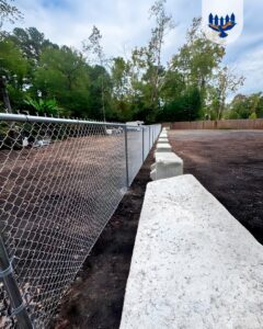 A durable chain-link fence with a concrete block base installed by Hawk Fences LLC in Johns Creek, GA.