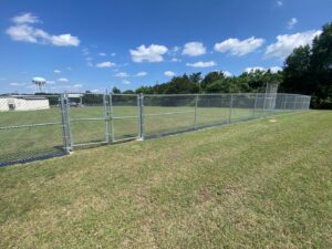 A long chain-link fence with double gates enclosing a large grassy area, installed by BAR Z Fencing and Welding LLC in Midlothian, TX