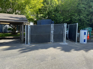 A newly installed chain-link fence with privacy slats and a double gate by Webb Fencing Pros in Seattle, WA.