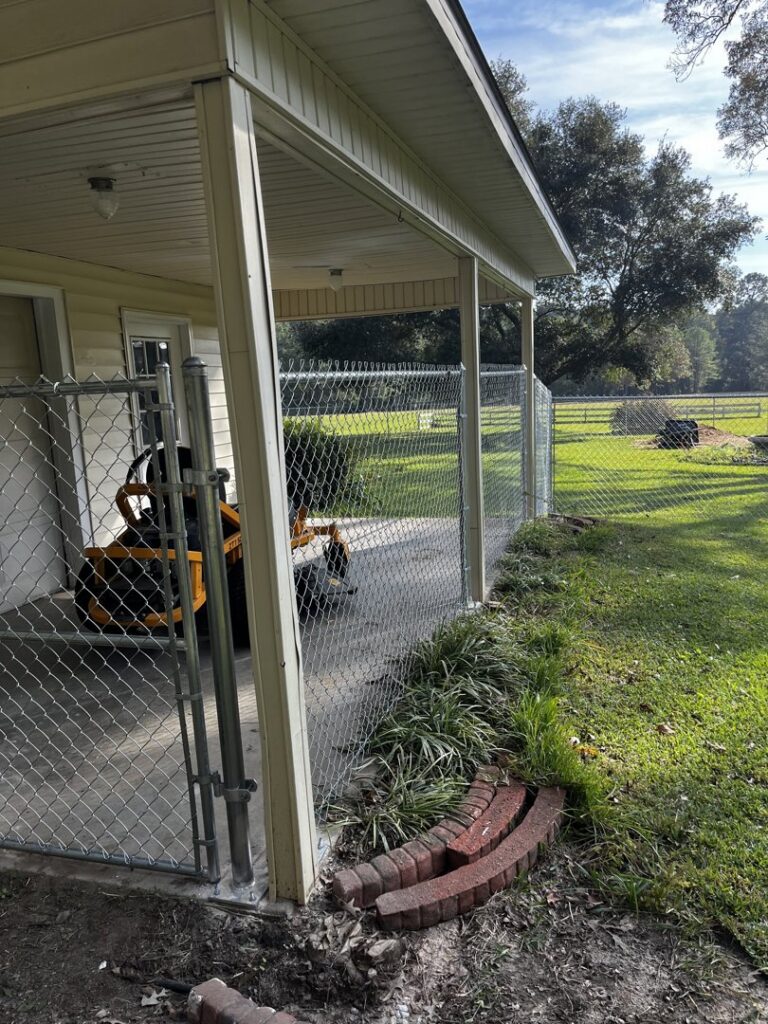 A chain-link fence installed to enclose a patio area next to a house by Dallas' Custom Carpentry in Alexandria, LA.
