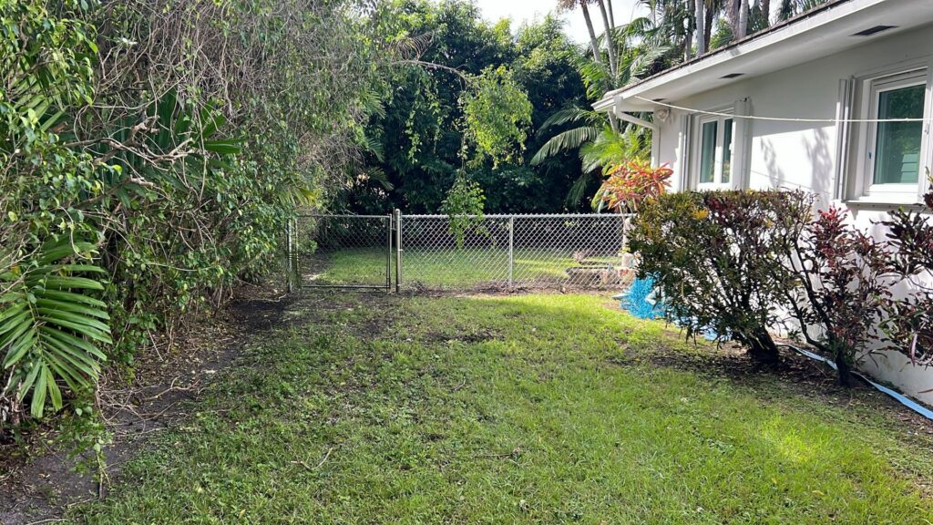 A chain link fence with a gate installed in a residential backyard by Palm's Fence of Miami, FL.