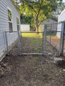 A chain-link fence gate installed in a narrow side yard between two houses by Dallas Fence in Dallas, TX.